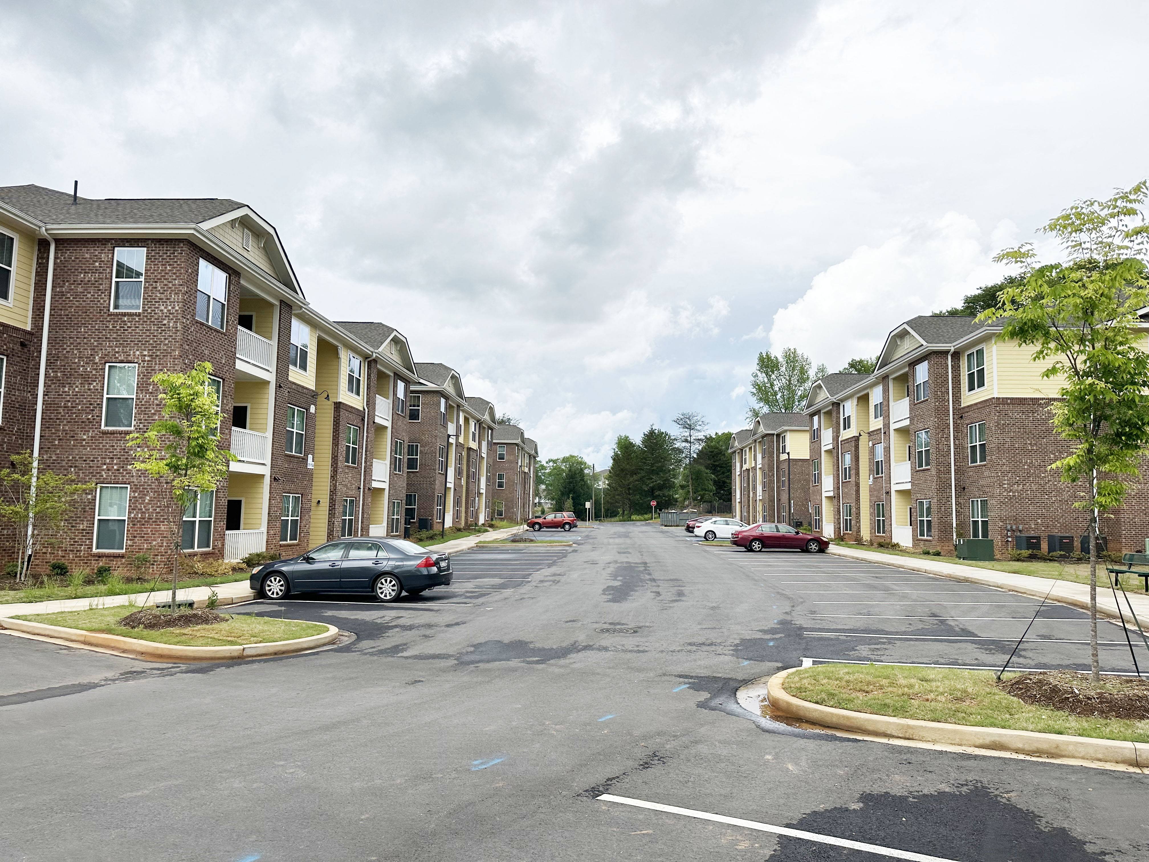 Creekside Village Apartments Exterior, with two buildings facing each other across a large parking lot and a few cars.